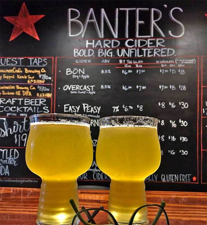 menu on chalkboard with two glasses of cider