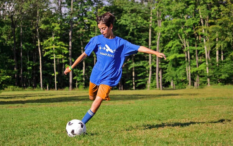 camp zeke camper kicking the soccer ball