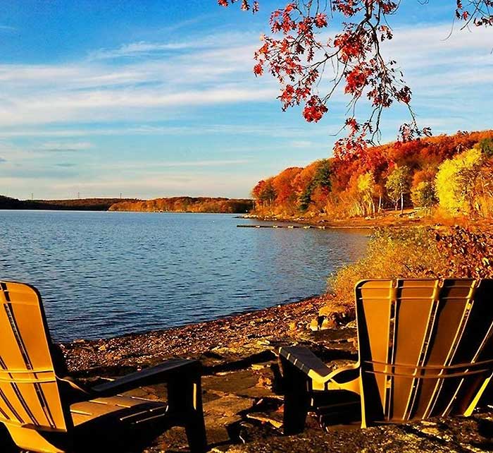 view of the lake with chairs from shore in autumn