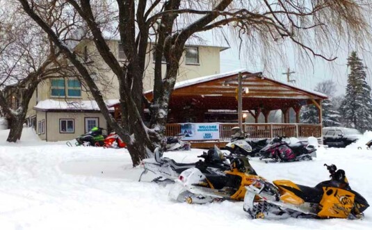 Lakewood restaurant exterior in the snow, deck and snowmobiles