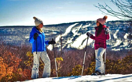 naturfi 2 women on mountain top on skis
