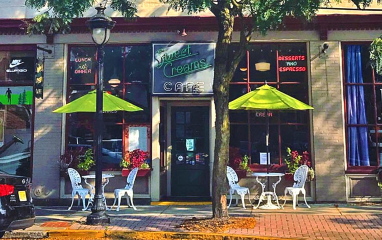 tables and umbrellas on sidewalk in front of store